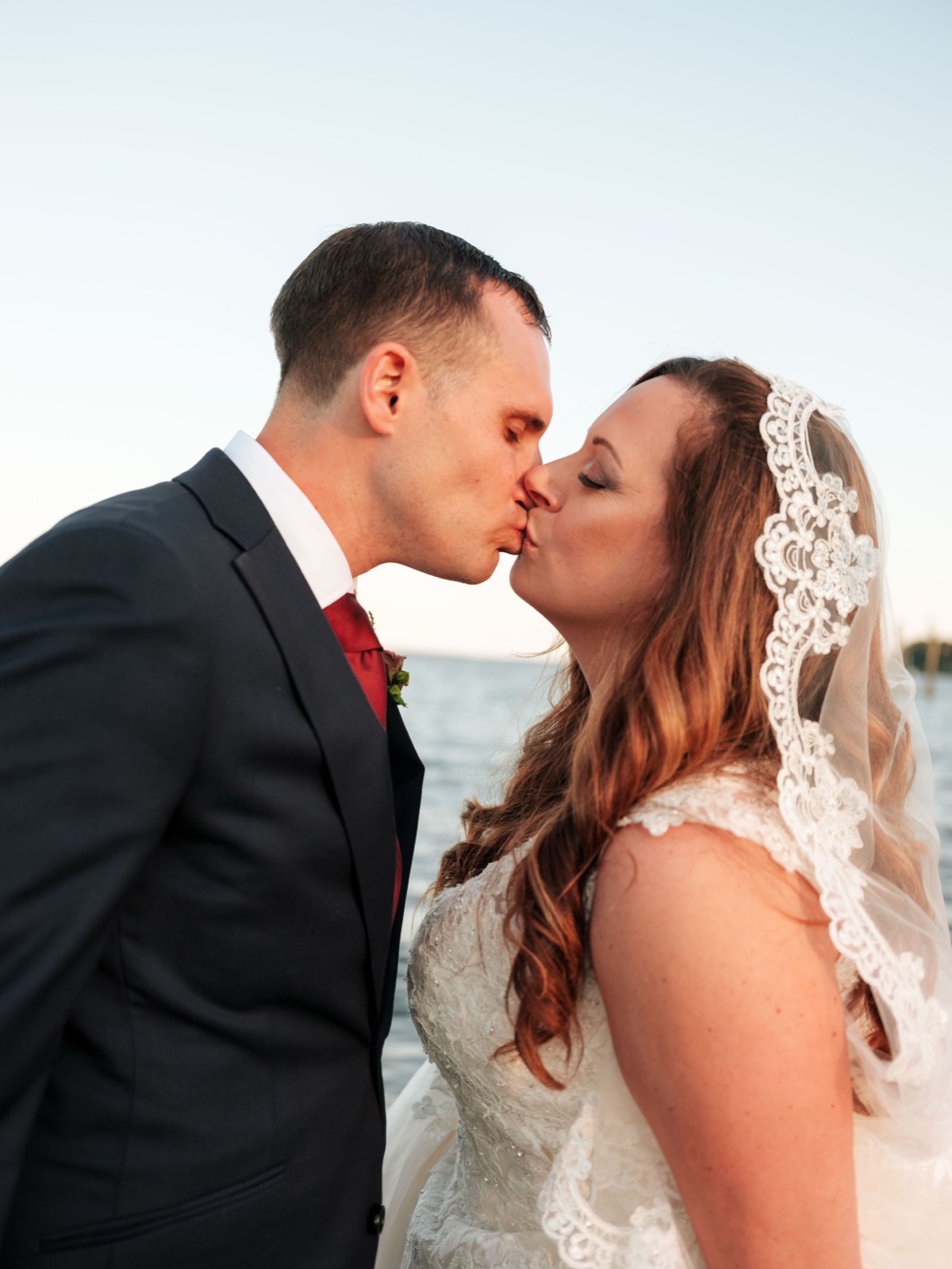 Emily and Adam kissing by the waterfront at Copper on the Neuse
